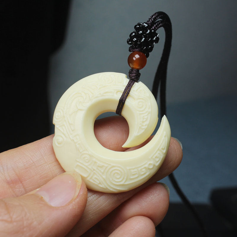 Ivory nut spiral pendant close-up showing carved geometric and cloud-like motifs