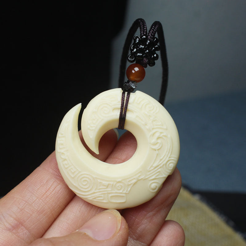 Hand-carved ivory nut spiral pendant with open crescent form and traditional relief pattern