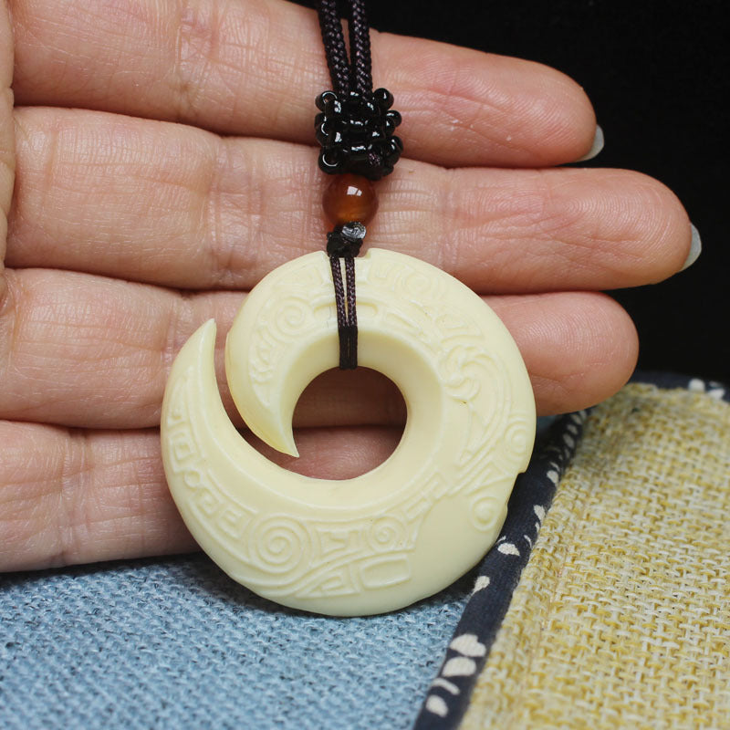Ivory nut spiral fortune pendant shown in hand with braided cord and bead accent