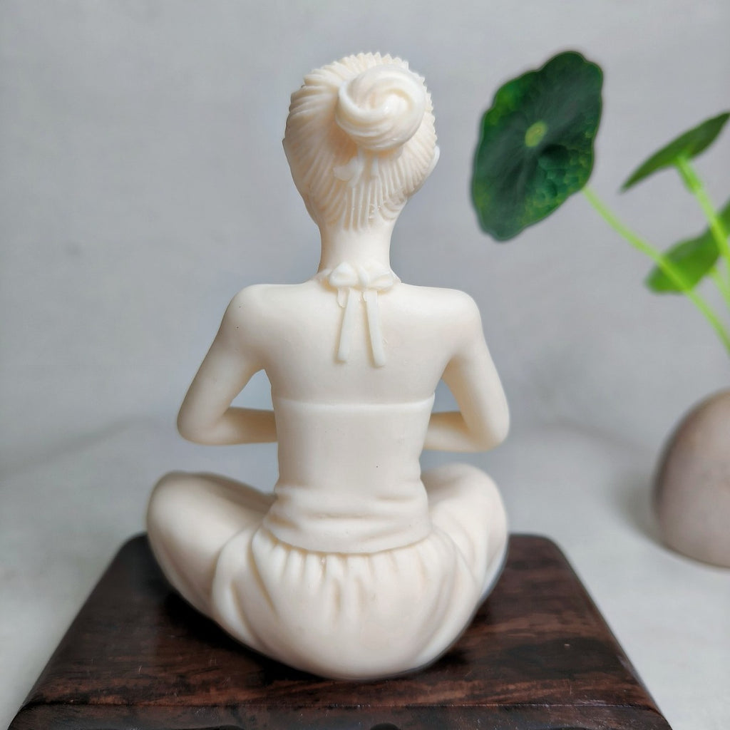 Back view of ivory nut yoga woman figurine with hair bun and seated posture
