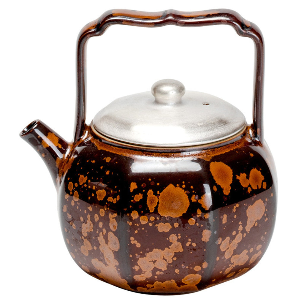 Close-up of chestnut brown kiln-transformed ceramic teapot with silver-tone lid and raised handle