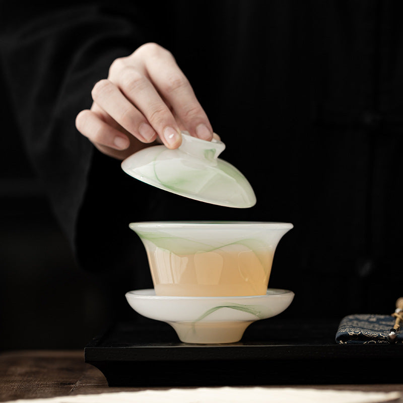 Floating green liuli gaiwan with lid lifted and brewed tea visible