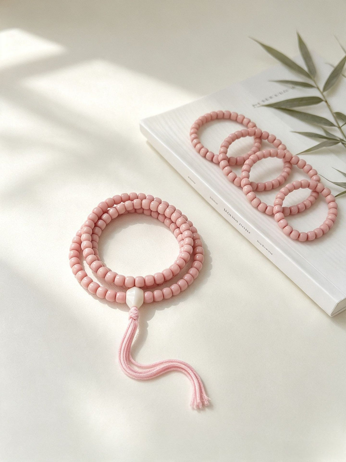 Pink Longji Bodhi old-style barrel bead bracelets and hand mala with tassel displayed in soft light