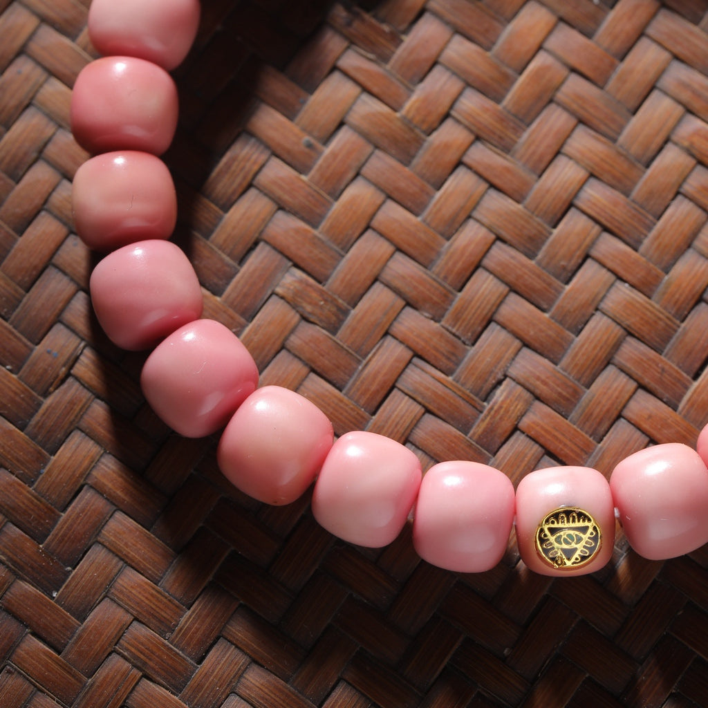Pink Longji Bodhi-style barrel bead close-up with Zaki-eye-style gold-tone marker bead