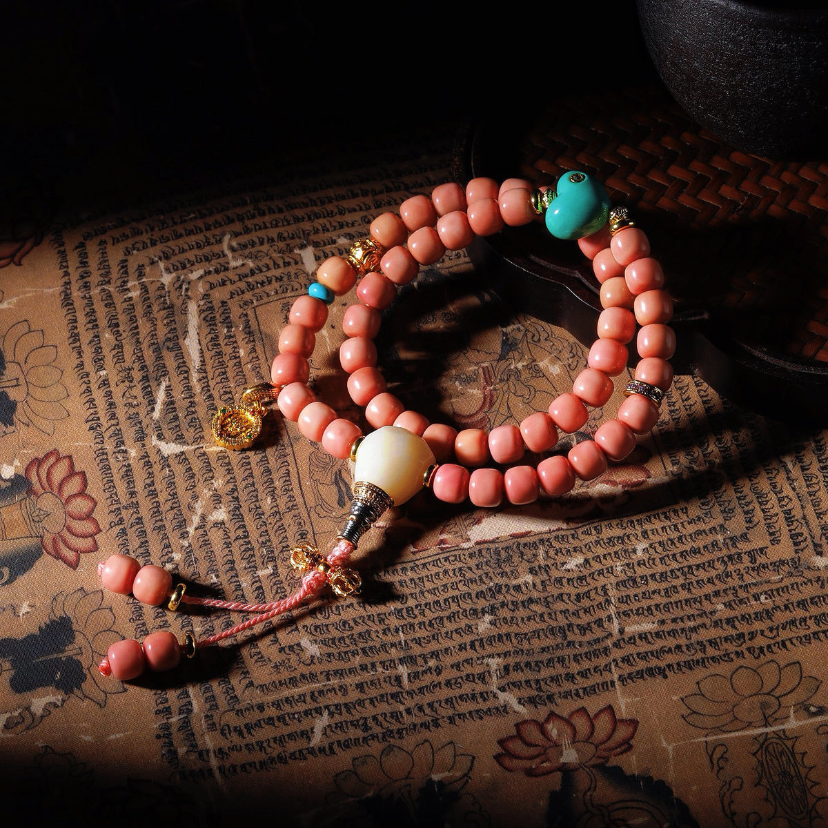 Pink Longji Bodhi hand mala with gourd-style pale focal piece, turquoise-tone accent and gold-tone charms