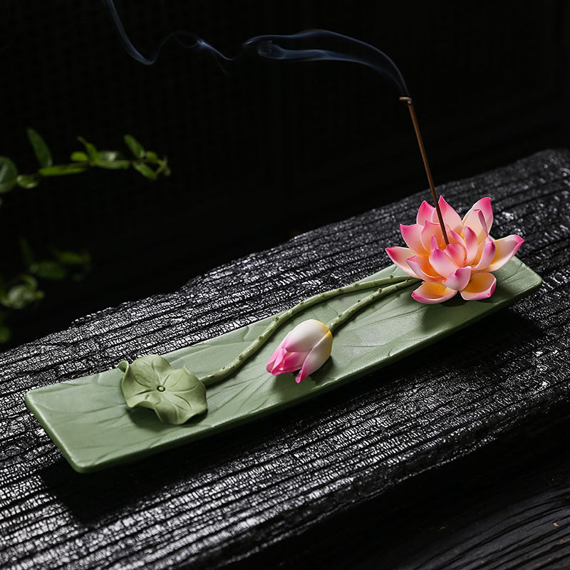 Coral pink lotus leaf incense stick holder in a dark Zen setting