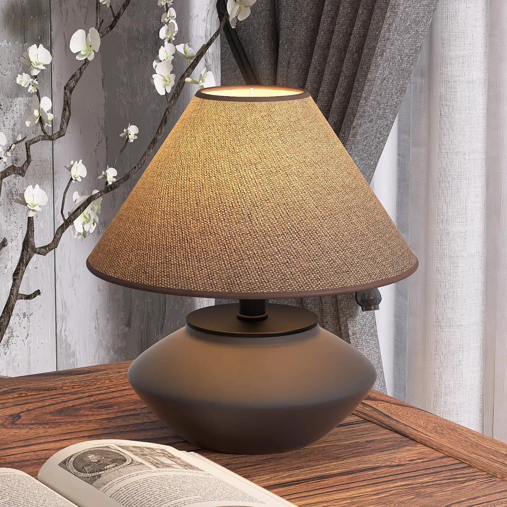Japanese-style low ceramic desk lamp beside open book and blossom branch
