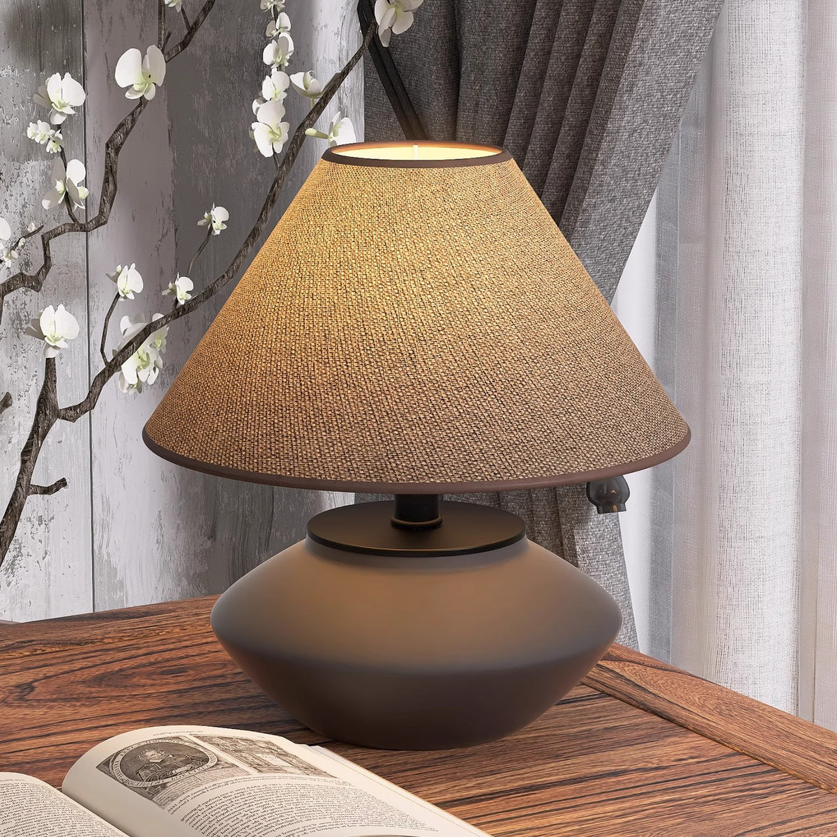 Japanese-style low ceramic desk lamp beside open book and blossom branch