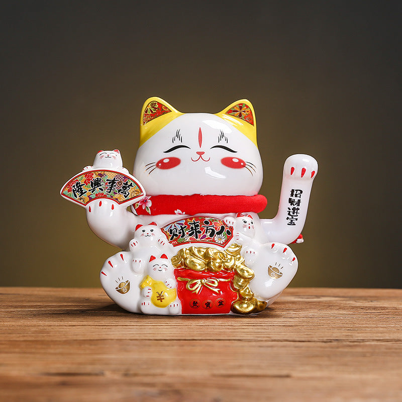 White red and gold lucky cat figurine holding fan and wealth symbols