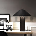 Matte black cone shade table lamp with cylindrical base on desk