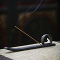 Minimalist matte black Buddha incense stick holder with long ash catcher and rising smoke