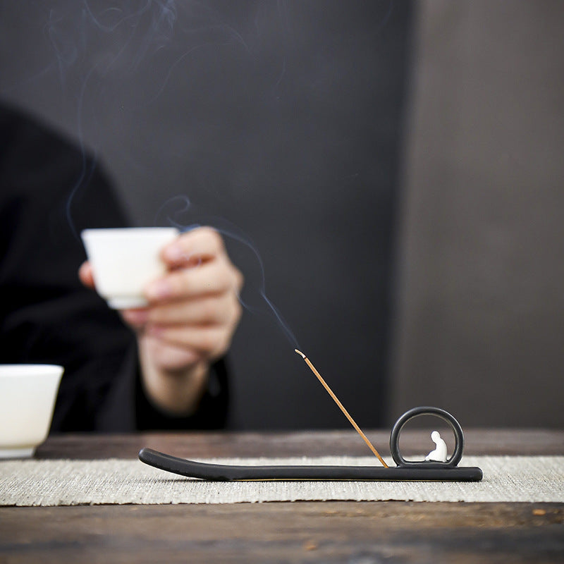 Slim Zen Buddha incense holder on tea table with incense stick