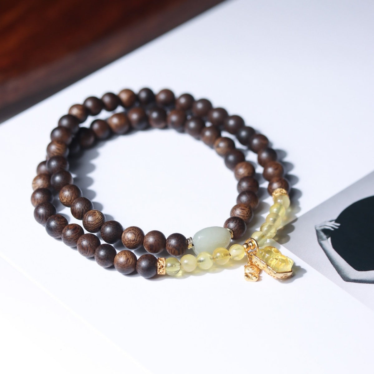 Natural agarwood double-wrap bracelet with amber-tone beads, pale jade-tone focal bead and gold-tone charms