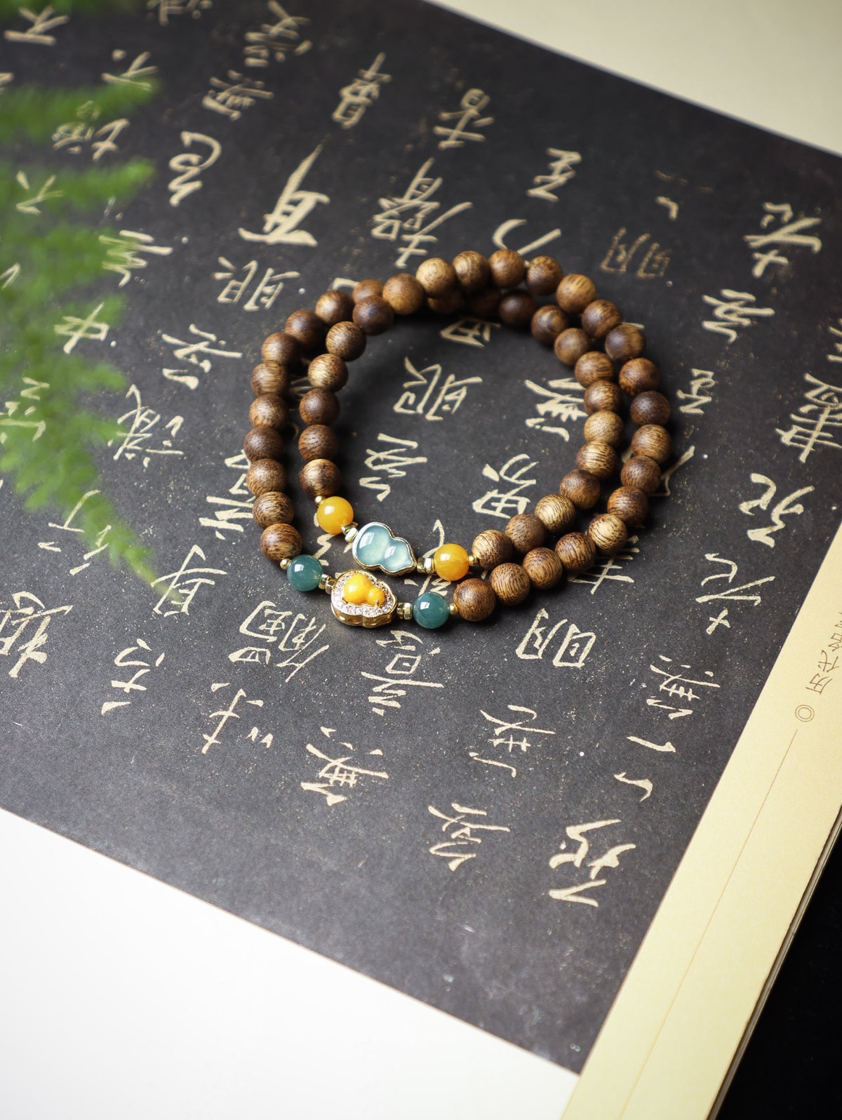 Natural agarwood double-wrap bracelet with blue-green and amber-tone accents and gourd-inspired focal charm