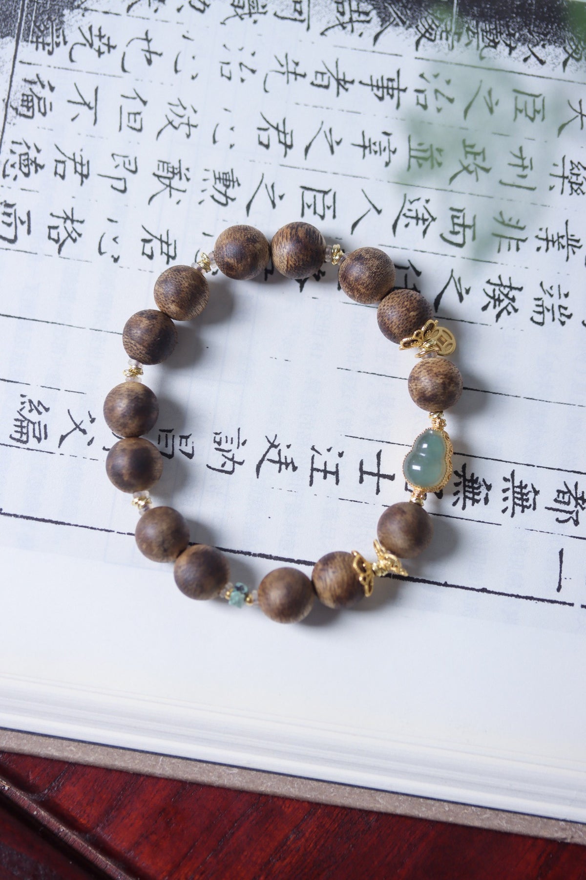 Natural agarwood 10mm bracelet with pale blue-green jade-tone focal accent and gold-tone charms