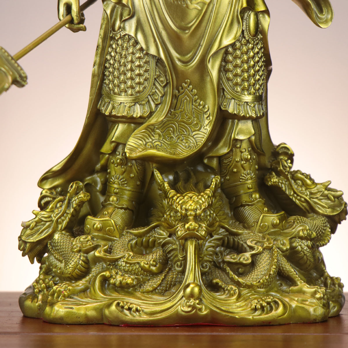 Close detail of Nine Dragon base on Chinese Guan Gong copperware statue with waves, armor, boots and dragon relief carving