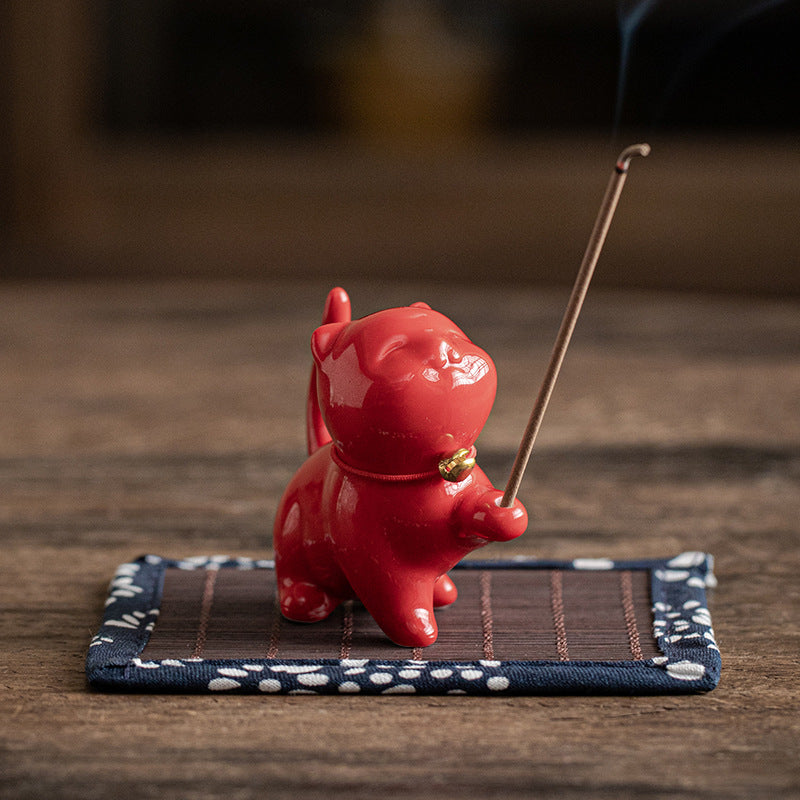 Cinnabar red ceramic cat incense stick holder on bamboo mat