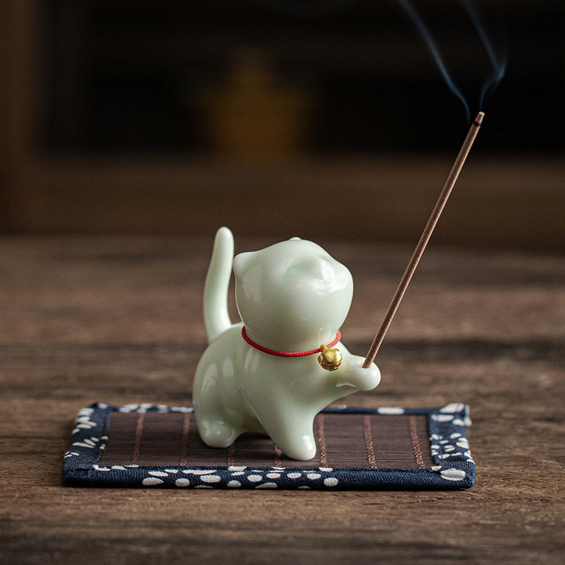 Celadon green ceramic cat incense holder on patterned mat
