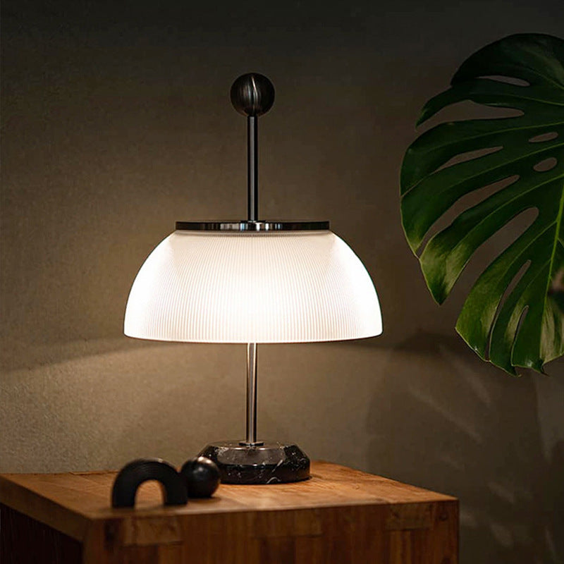 Pearl black ribbed glass dome table lamp glowing on wood side table