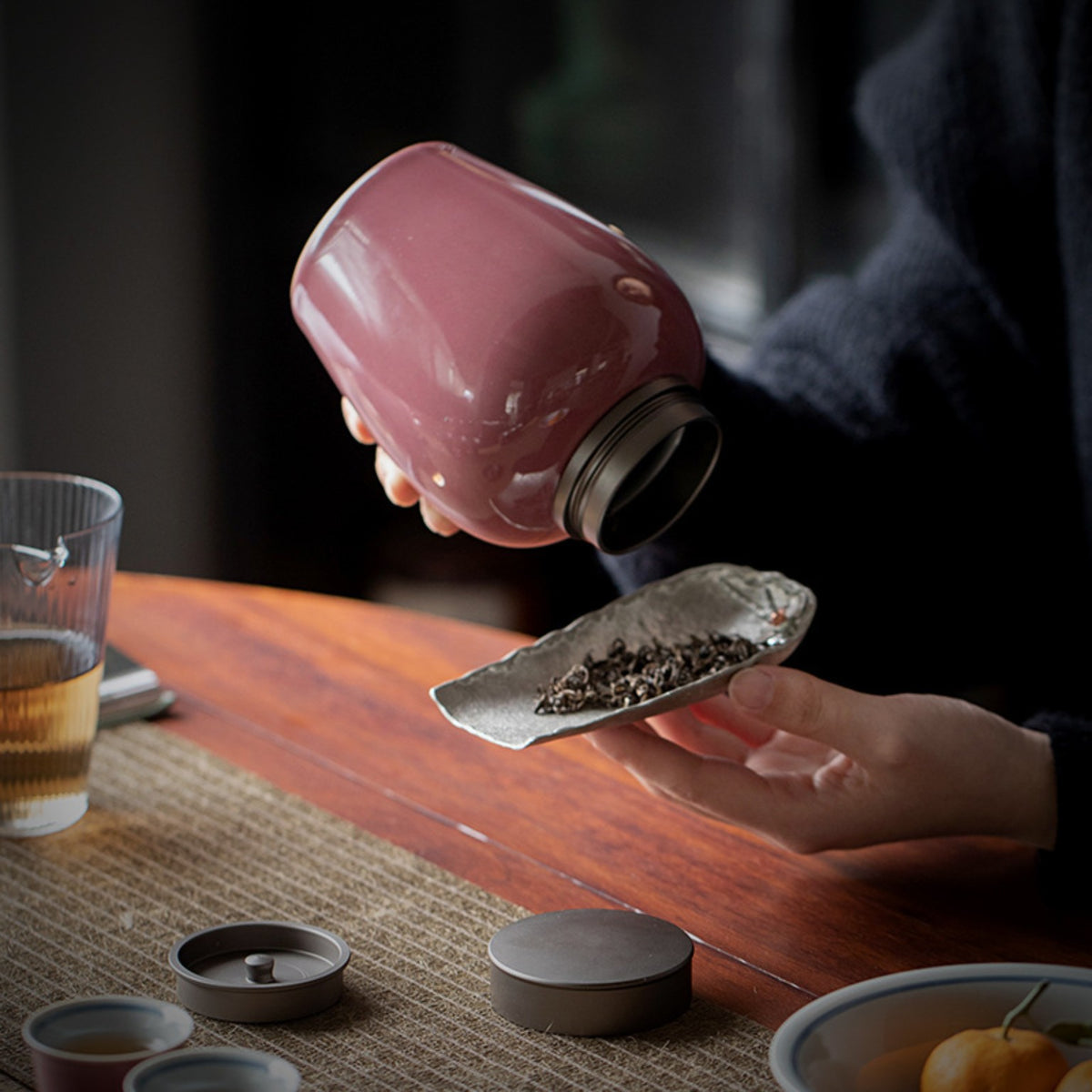 Pink ceramic loose leaf tea storage jar in use with double airtight lid