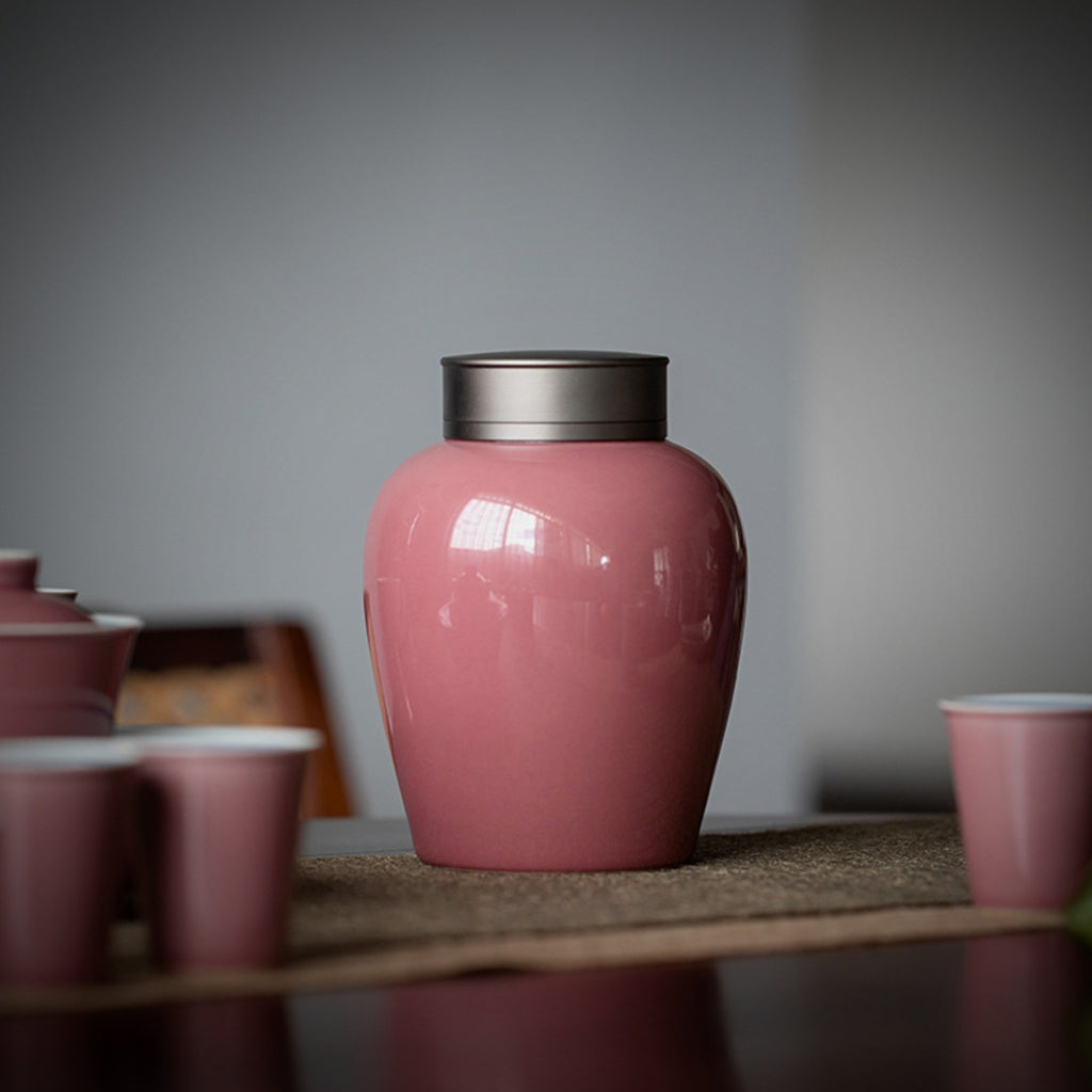 Pink ceramic tea canister displayed with matching Chinese teaware