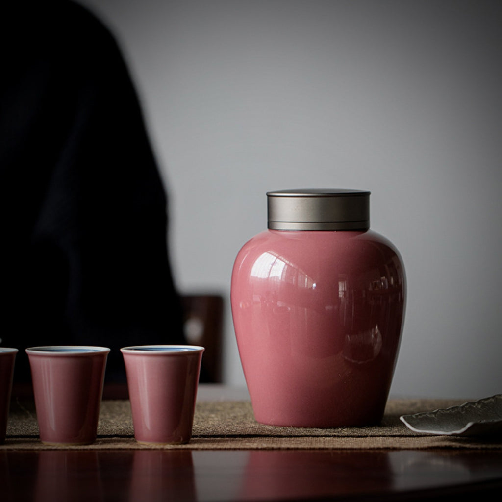 Pink ceramic tea storage jar beside Gongfu tea cups