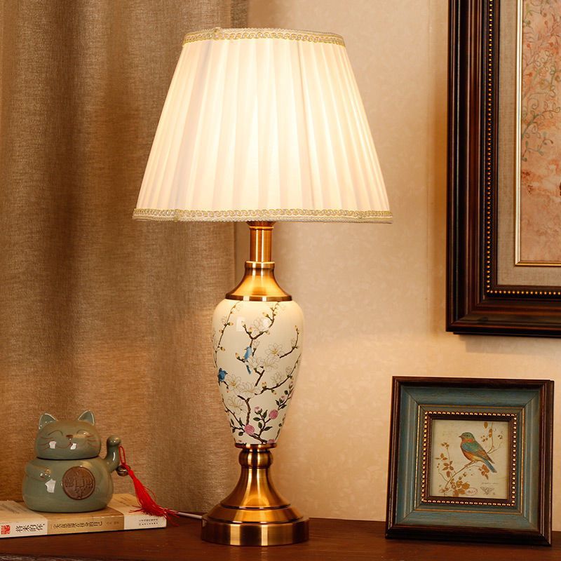 Magnolia branch porcelain table lamp with pleated shade and antique brass-tone fittings
