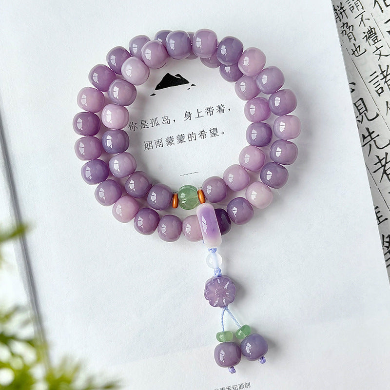 Purple and lilac Bodhi root double-wrap hand mala with decorative tassel photographed on a book for tea-room and study styling