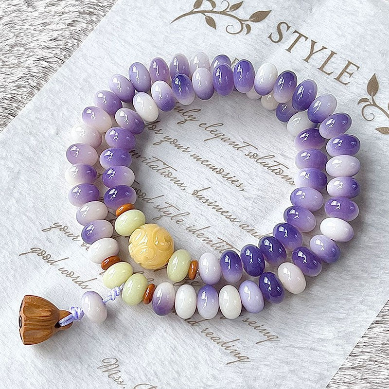 Purple and white Bodhi root double-wrap bracelet with pale green and yellow accents and lotus-pod style charm