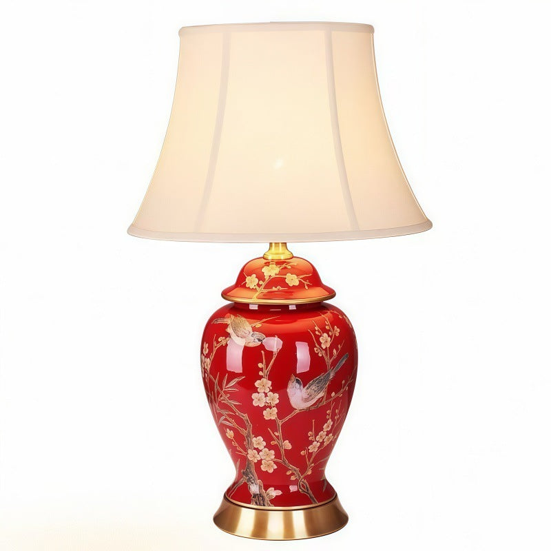 Red chinoiserie ceramic lamp with white fabric shade on clean background