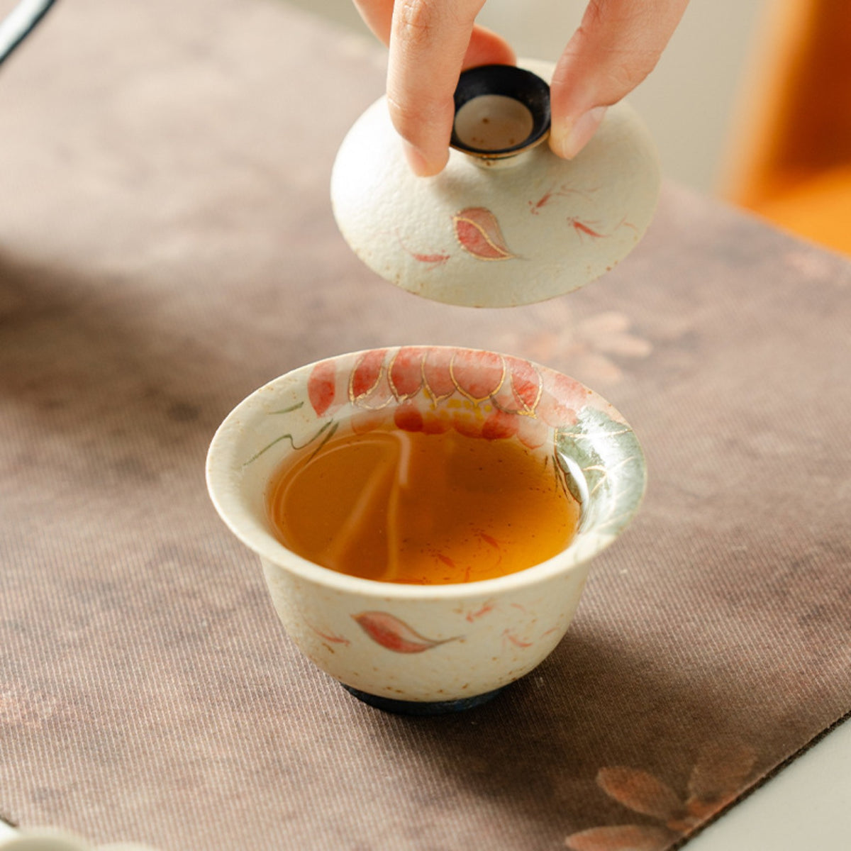 Hand-painted red koi and lotus 150ml gaiwan with tea, shown in use