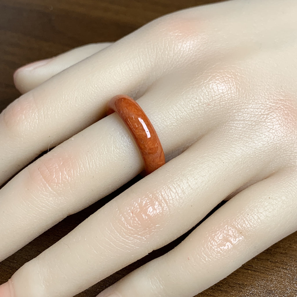 Warm red orange jadeite band ring worn on hand showing slim minimalist profile