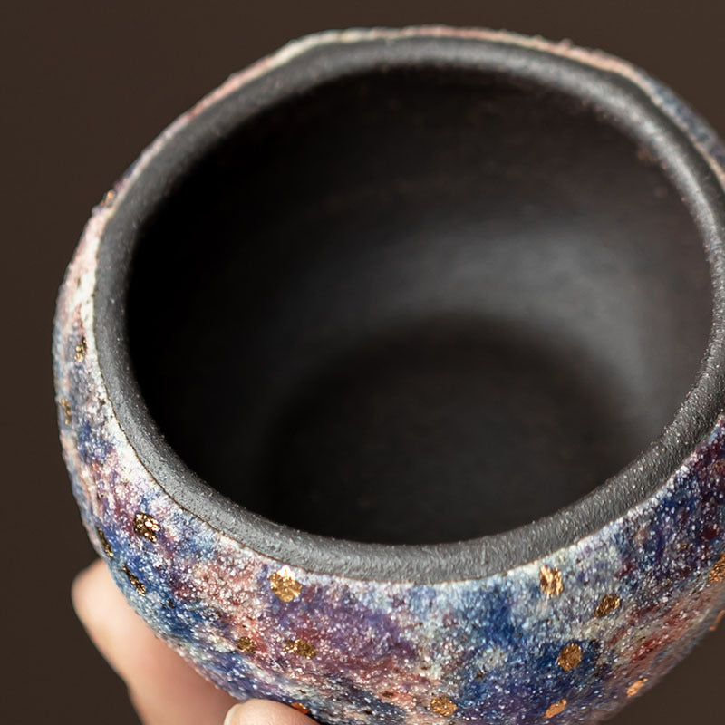 Close view of dark ceramic interior and mineral-textured exterior of Gongfu tea cup