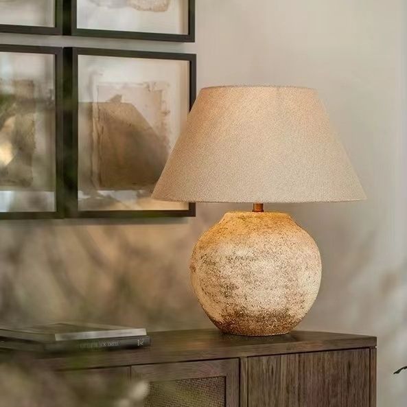 Round stone-finish ceramic table lamp with warm linen shade in neutral interior