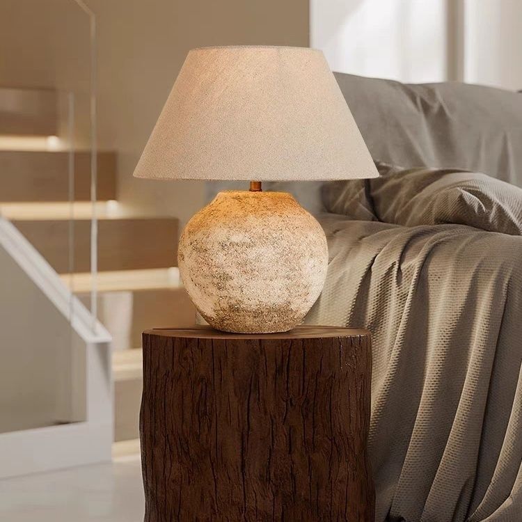 Round textured ceramic lamp styled on dark wood bedside table