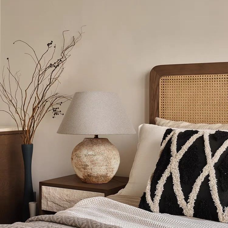 Round ceramic table lamp with linen shade in wabi-sabi rattan bedroom