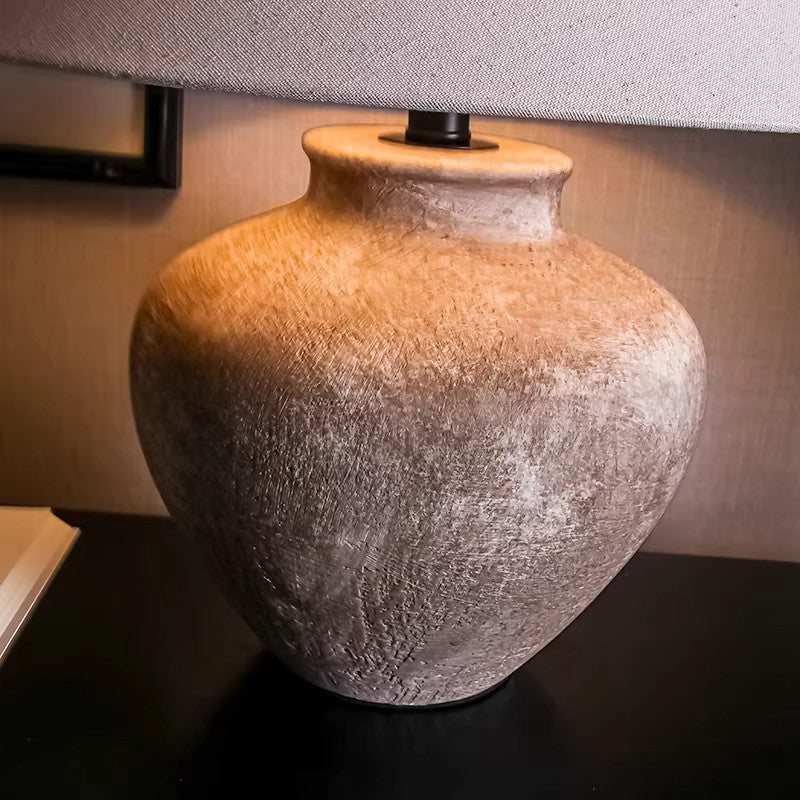 Rustic aged ceramic jar table lamp with warm linen shade and textured surface