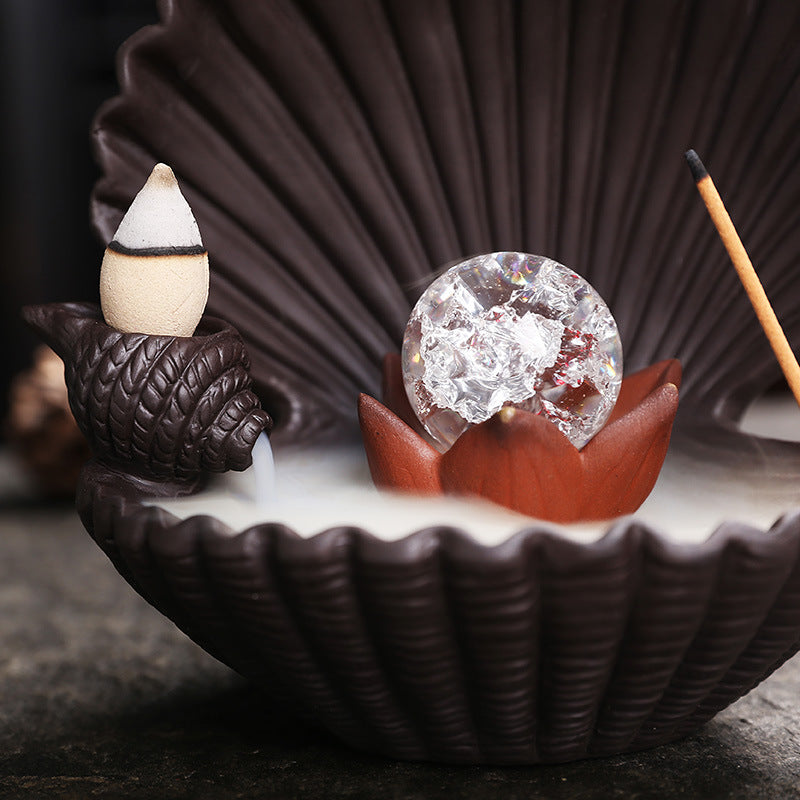 Close-up shell incense burner with clear crackle orb and backflow cone