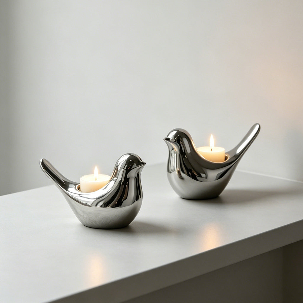 Pair of polished silver ceramic bird candle holders with candles