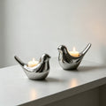 Pair of polished silver ceramic bird candle holders with candles