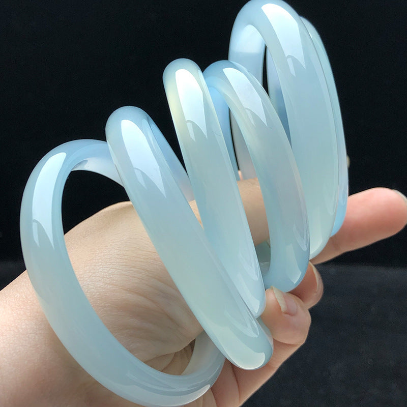Icy blue chalcedony bangle collection held in hand for scale