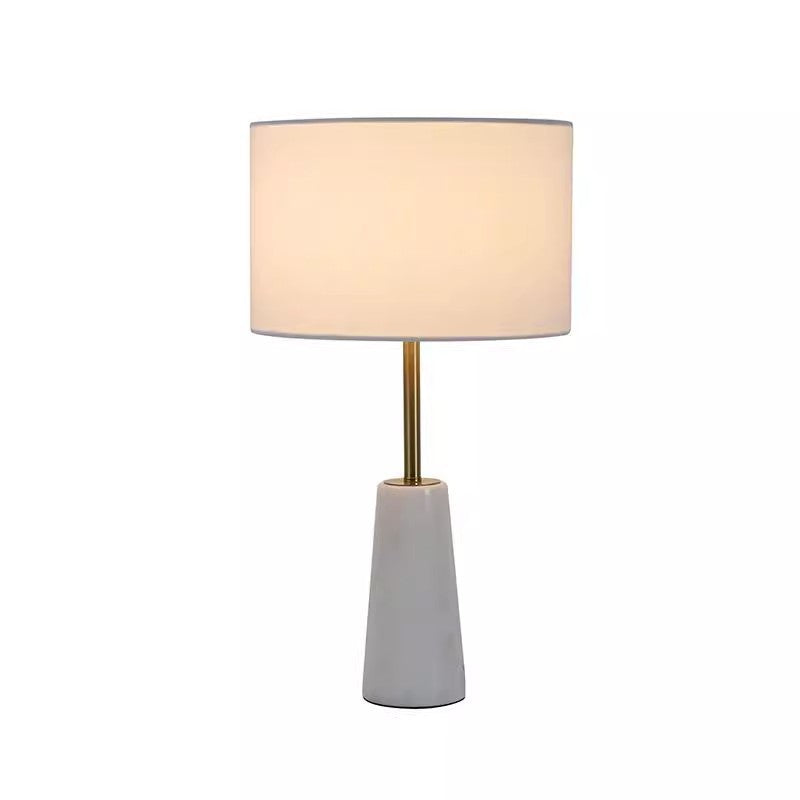 Small white tapered marble table lamp with slim brass stem and fabric drum shade