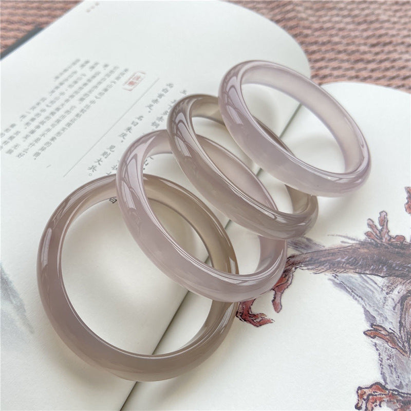 Smoky gray and lilac chalcedony bangles styled on open book