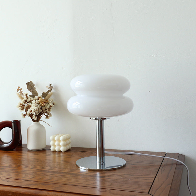 Milk white stacked glass cake lamp styled on wood console with flowers