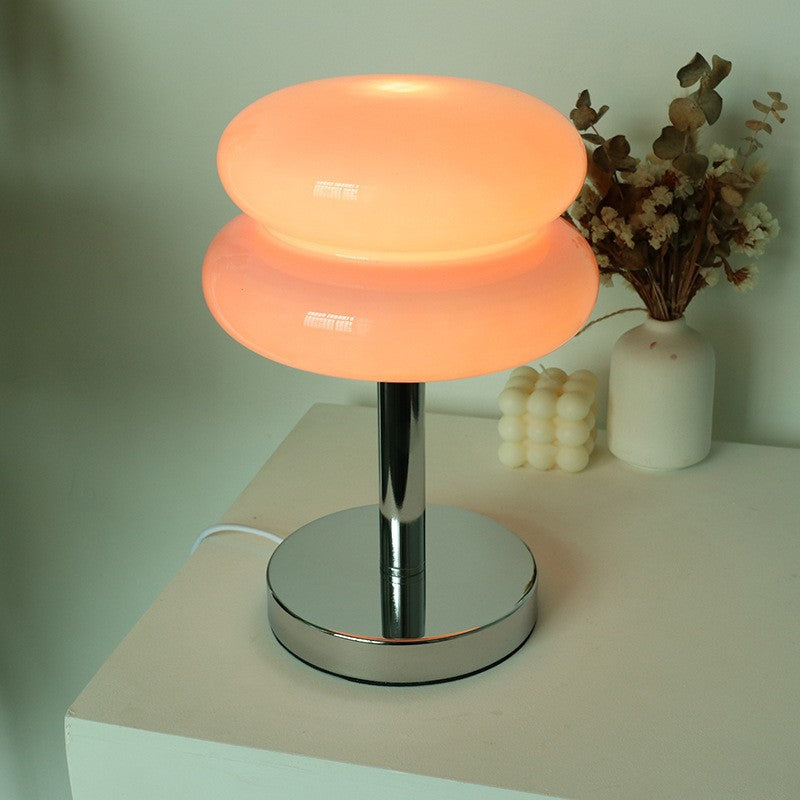 Powder pink stacked glass cake lamp glowing in a soft pastel interior