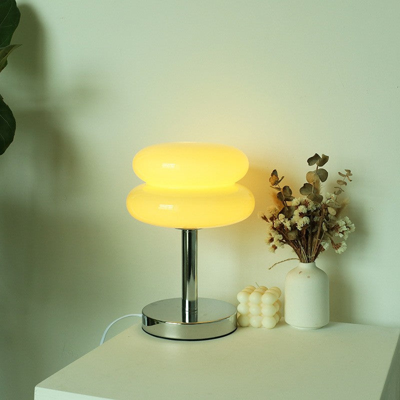 Milk yellow stacked glass cake table lamp glowing beside floral decor