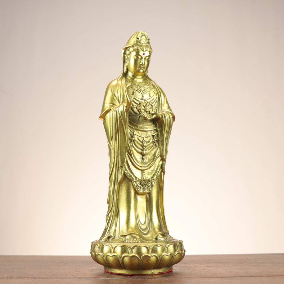 Three-quarter view of standing Guanyin Bodhisattva copperware statue holding a Dharma wheel on lotus base