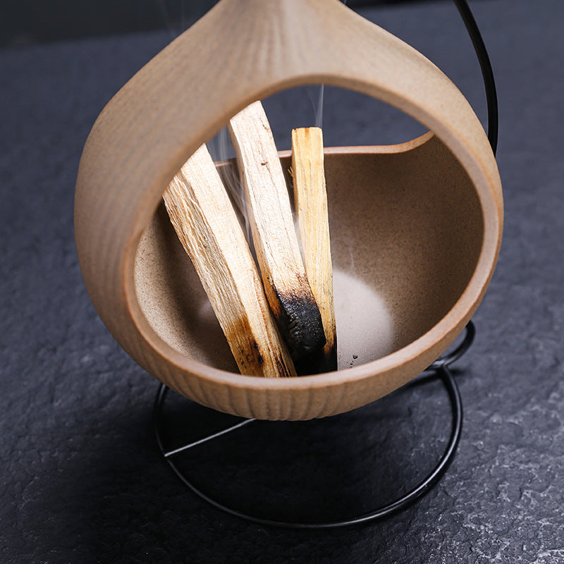 Palo Santo wood burning inside hanging teardrop ceramic holder
