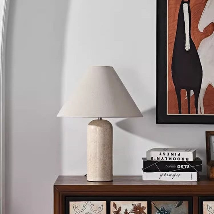 Travertine cylinder table lamp styled on console beside abstract artwork