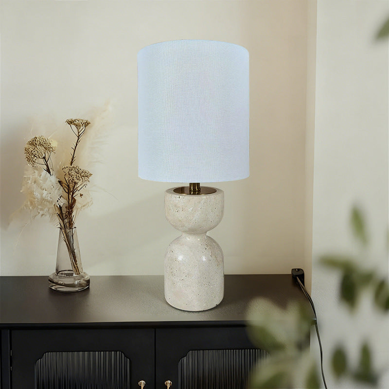 Travertine hourglass table lamp with white fabric shade in modern interior